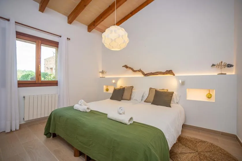 Un dormitorio luminoso con una cama grande vestida con ropa de cama blanca y verde.