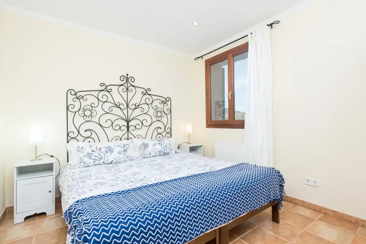 Un dormitorio con una colcha estampada y una ventana junto a la cama.