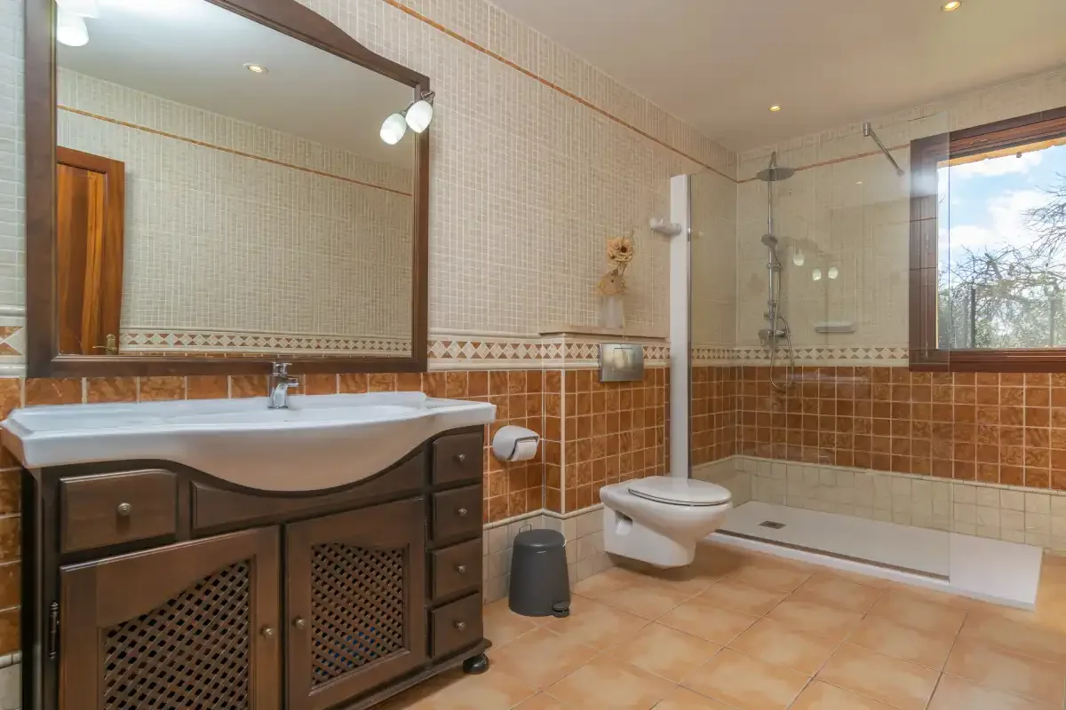 Un baño alicatado con lavabo y ducha de vidrio.