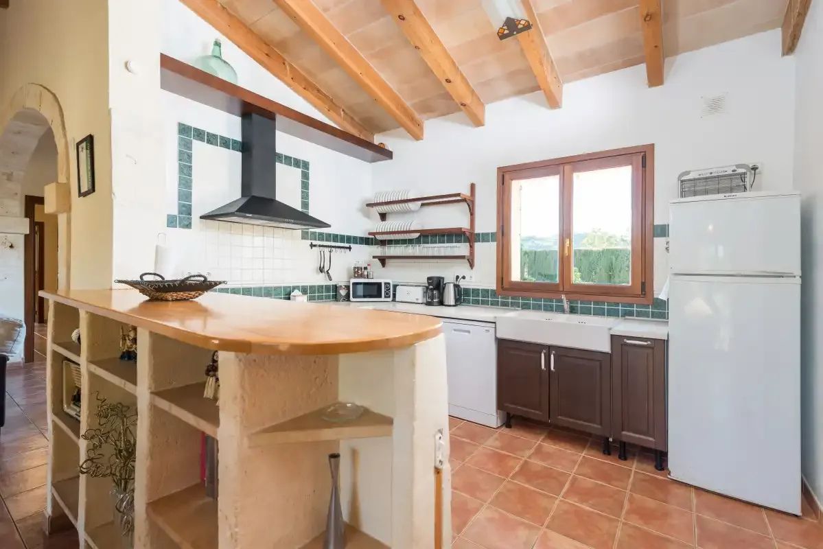 Una cocina luminosa con una isla de madera y gabinetes bajo una ventana grande.