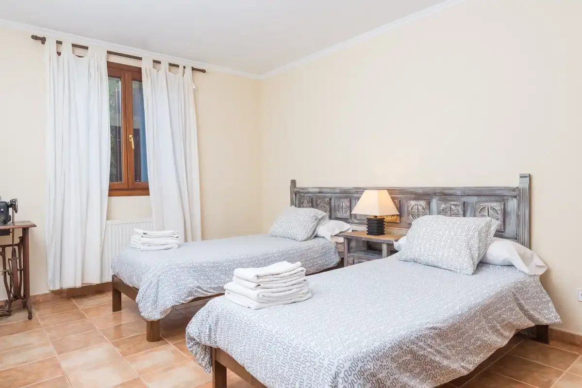 Un dormitorio con dos camas, una mesita de noche y una ventana con cortinas.