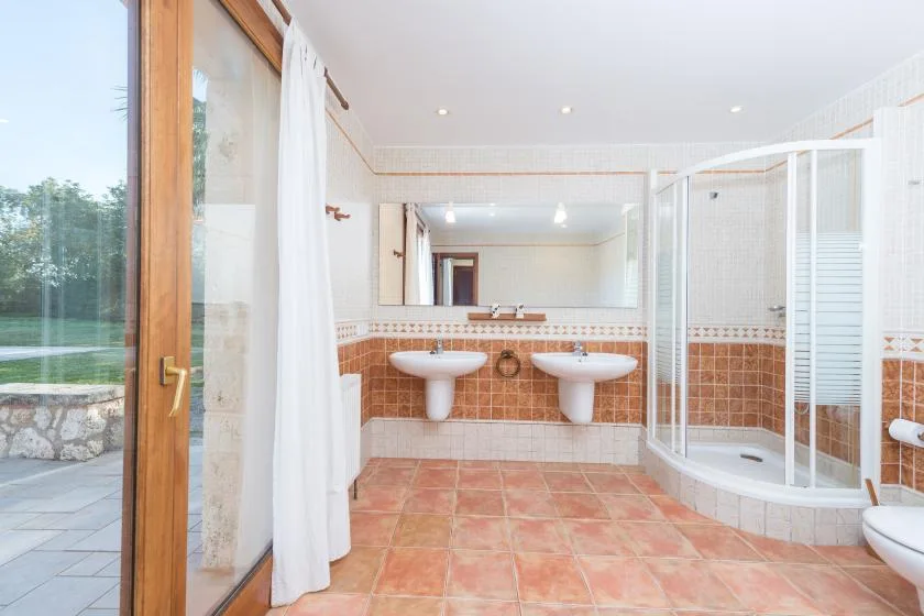 Un baño amplio con dos lavabos, un espejo grande y una ducha de vidrio.