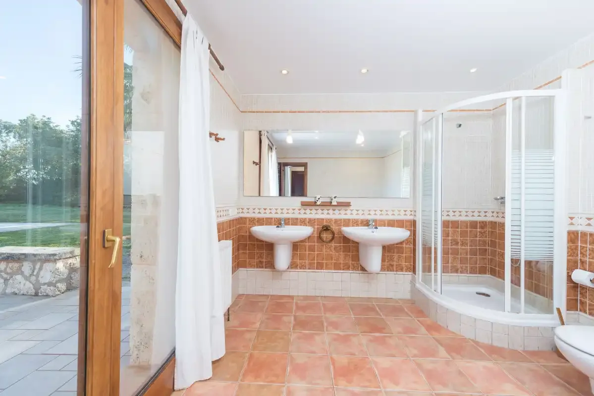 Un baño con azulejos, dos lavabos y una ducha de cristal.