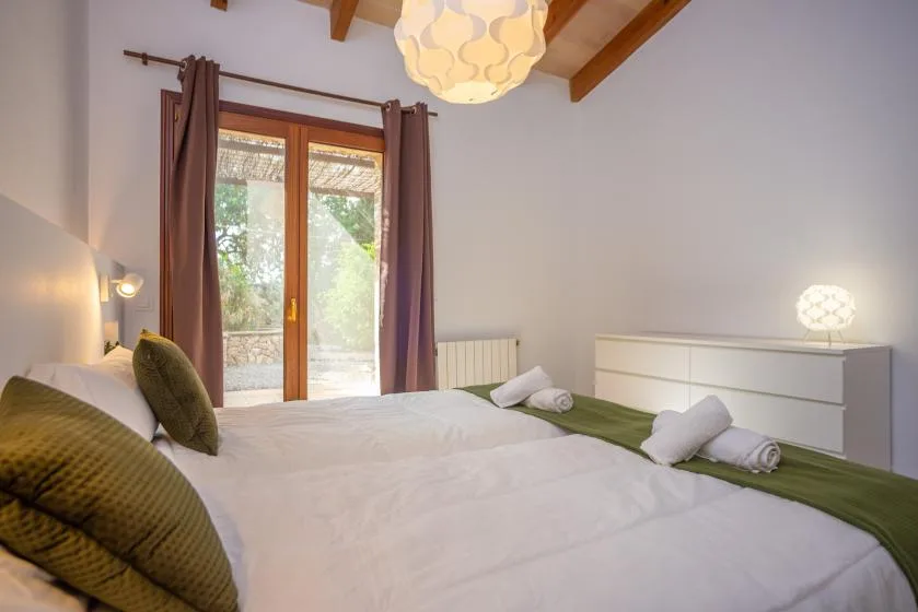Un dormitorio con una cama grande, ropa de cama verde y puertas de vidrio que dan a un patio.
