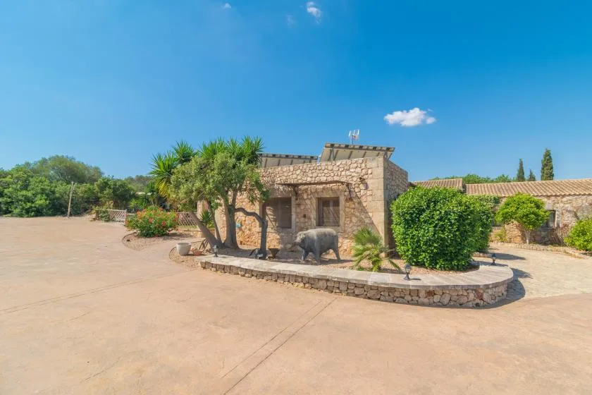 Un edificio de piedra está junto a un patio pavimentado con palmeras y arbustos.