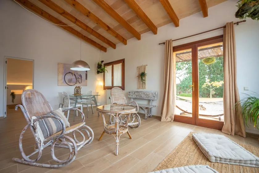 Una sala luminosa con asientos de mimbre y puertas de vidrio que dan al jardín.