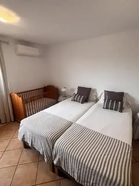 Un dormitorio con dos camas individuales y ropa de cama a rayas junto a una cuna de madera.