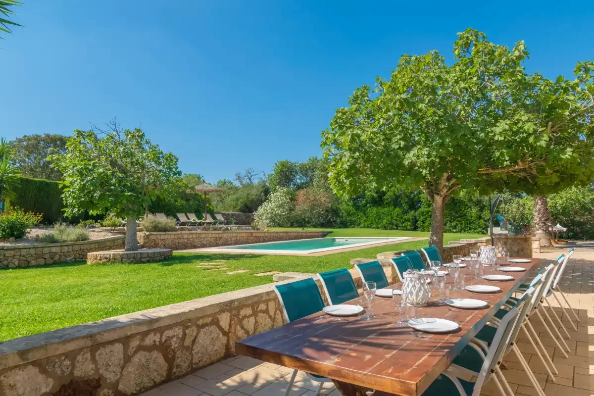 Una zona de comedor al aire libre junto a un césped y una piscina.