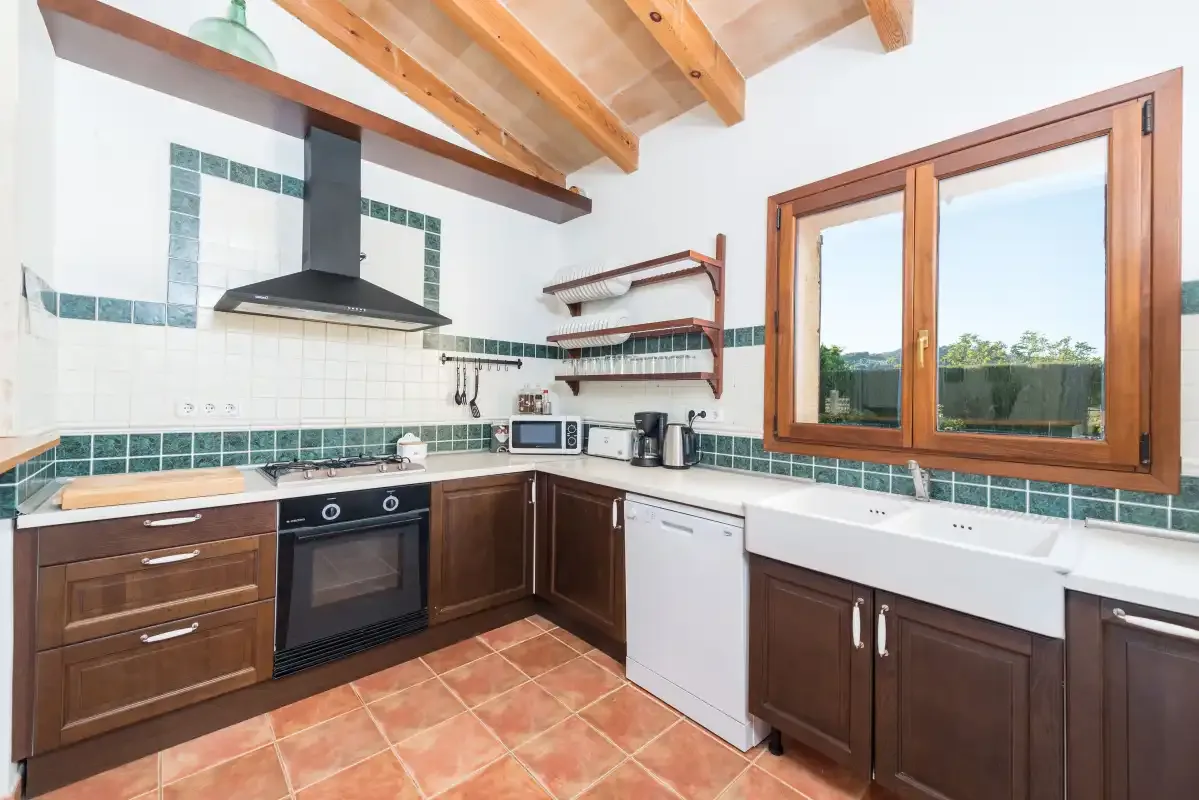 Una cocina con muebles oscuros, un salpicadero de azulejos y una ventana grande.