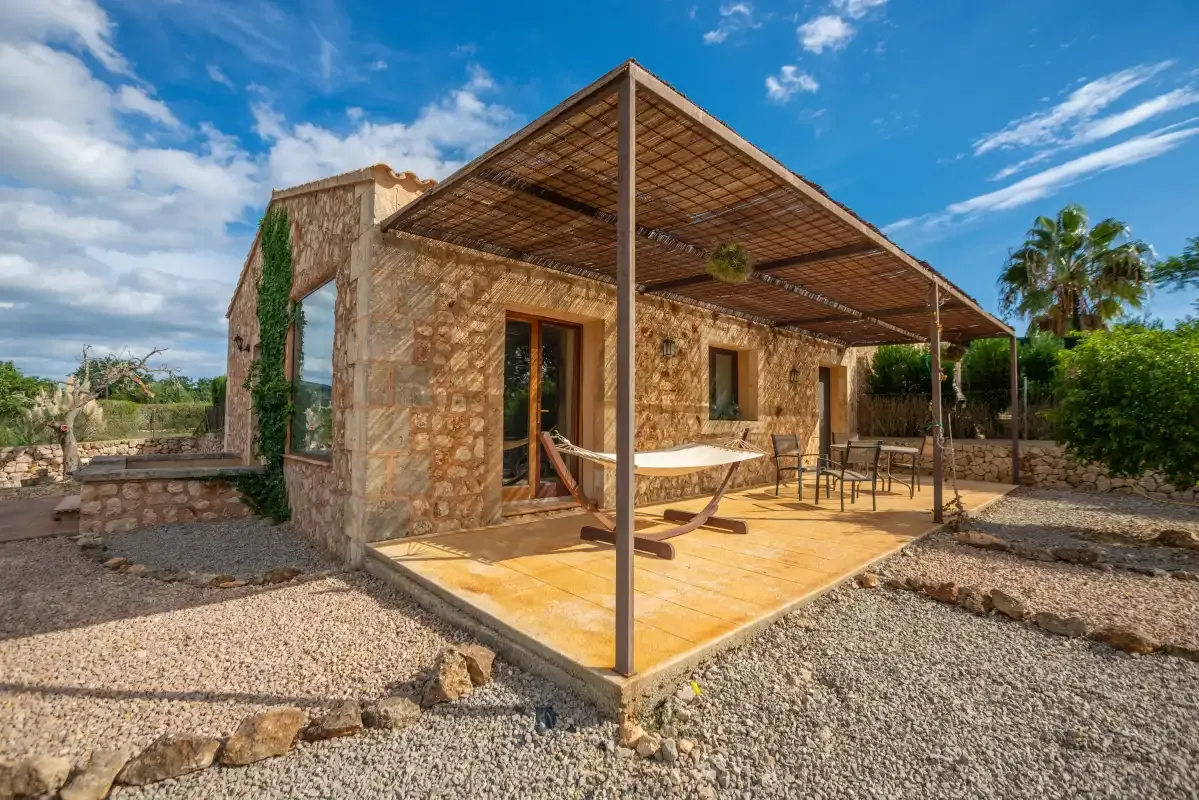 Una casa de piedra tiene un patio cubierto con asientos al aire libre.
