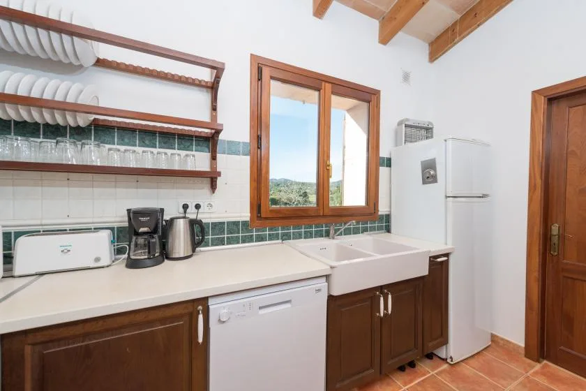 Una cocina con fregadero, pequeños electrodomésticos y una ventana.