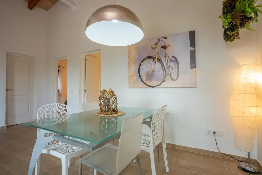Un comedor con una mesa de cristal y una lámina de una bicicleta en la pared.