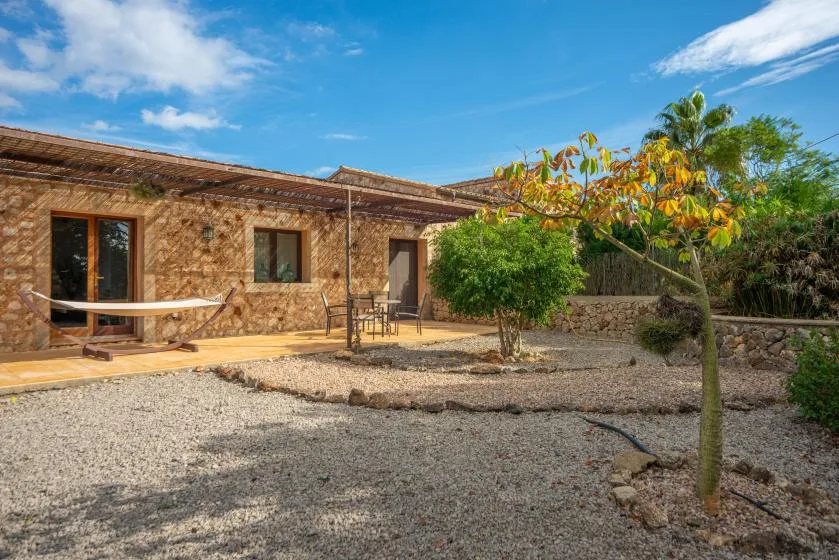 Un edificio de piedra da a un patio de grava con árboles y asientos al aire libre.
