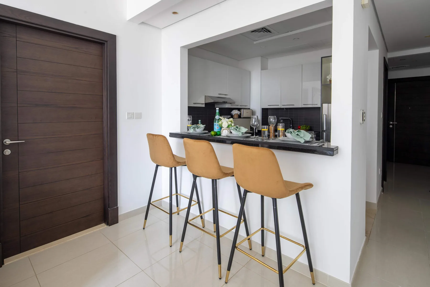 A kitchen counter with bar seating and a dark wooden door.