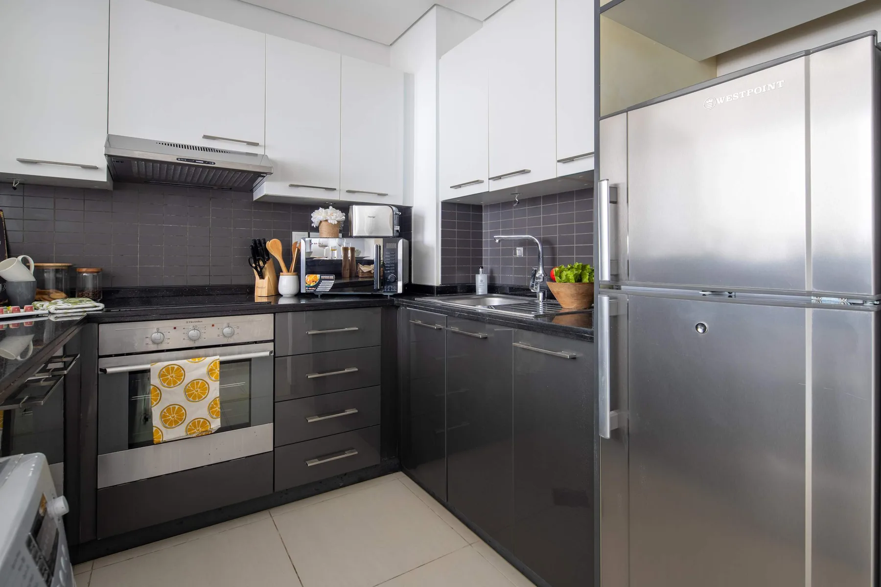 A modern kitchen with dark cabinetry, a countertop, and stainless steel appliances.
