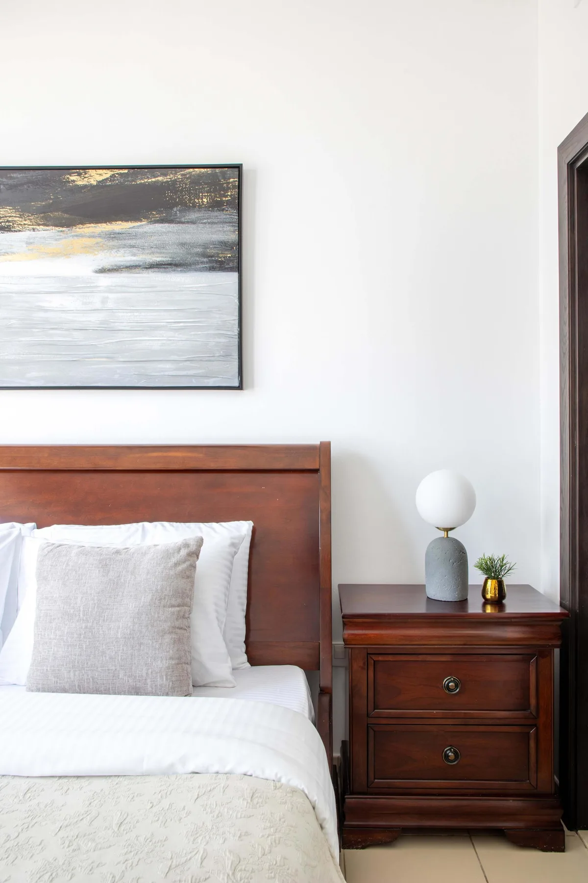 A bedroom with a neatly made bed and a wooden bedside table.