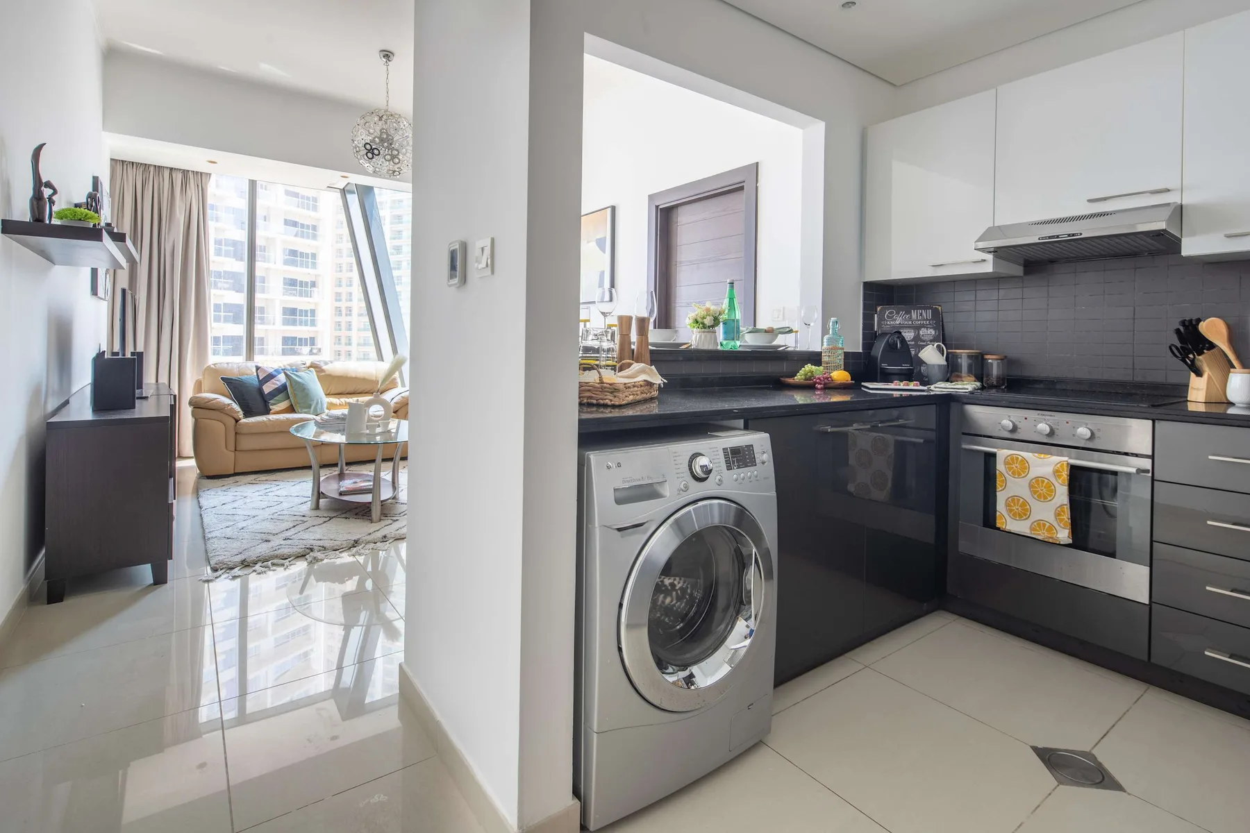 A modern kitchen with dark countertops and a washing machine beside the oven.