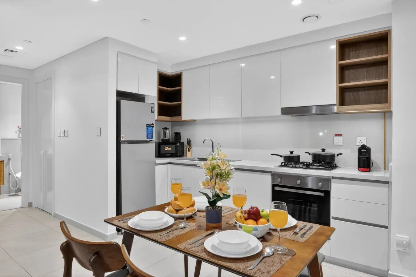 Una cocina moderna y luminosa con gabinetes blancos y una mesa preparada para comer.