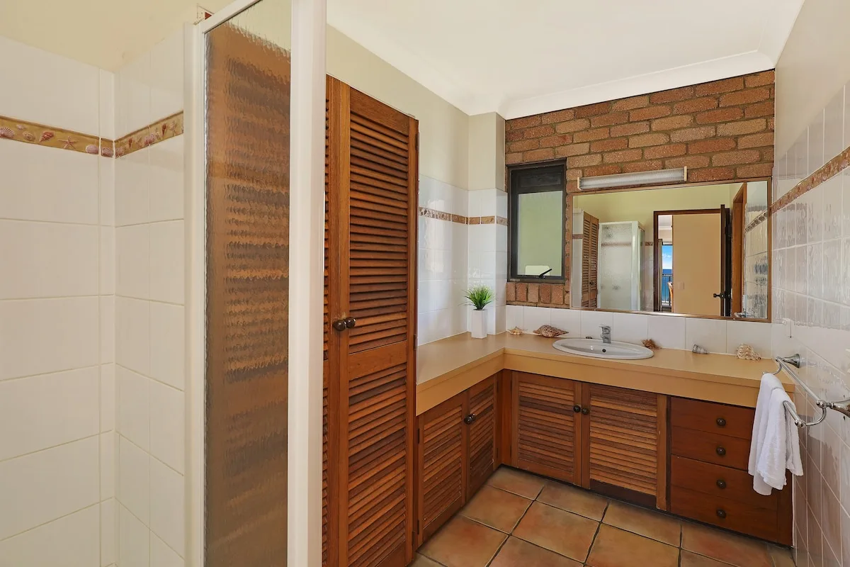 A bathroom with a long vanity, mirrored wall, and tiled floor.