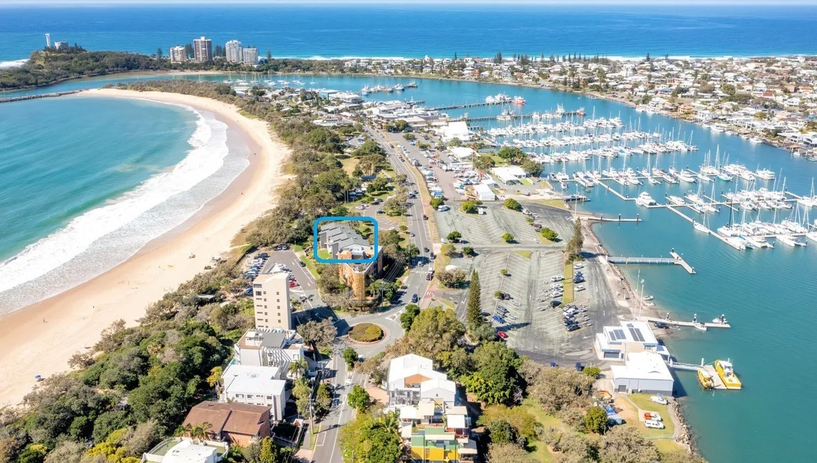 Aerial view of a coastal town with a curved beach and marina.