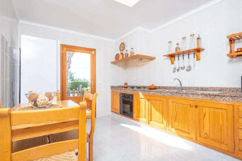 Una cocina luminosa con gabinetes de madera, una encimera y una mesa de comedor.
