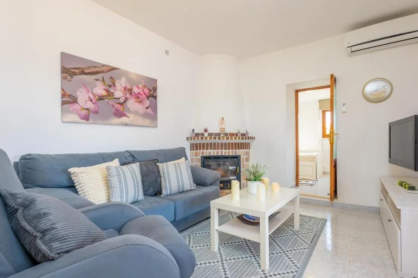 Una sala de estar con asientos azules, una mesa de centro y una chimenea.