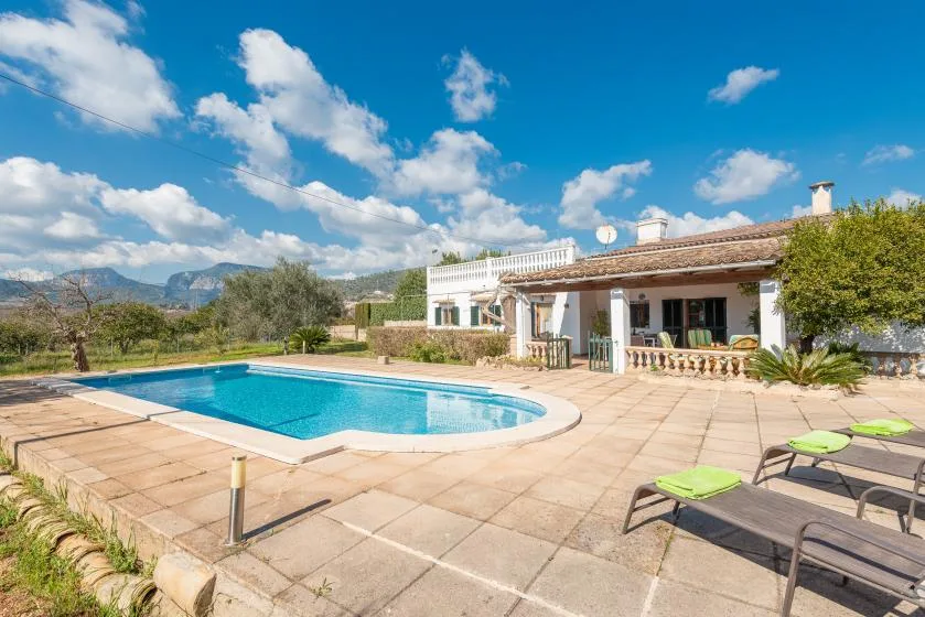 Una piscina y un patio pavimentado están junto a una casa de una planta.