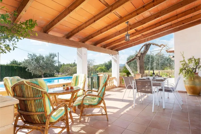 Un patio exterior cubierto con muebles de comedor da a una piscina y un jardín.