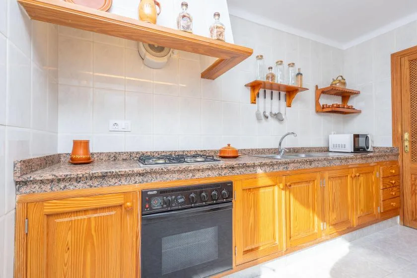 Una cocina con azulejos, gabinetes de madera, una encimera y un horno empotrado.