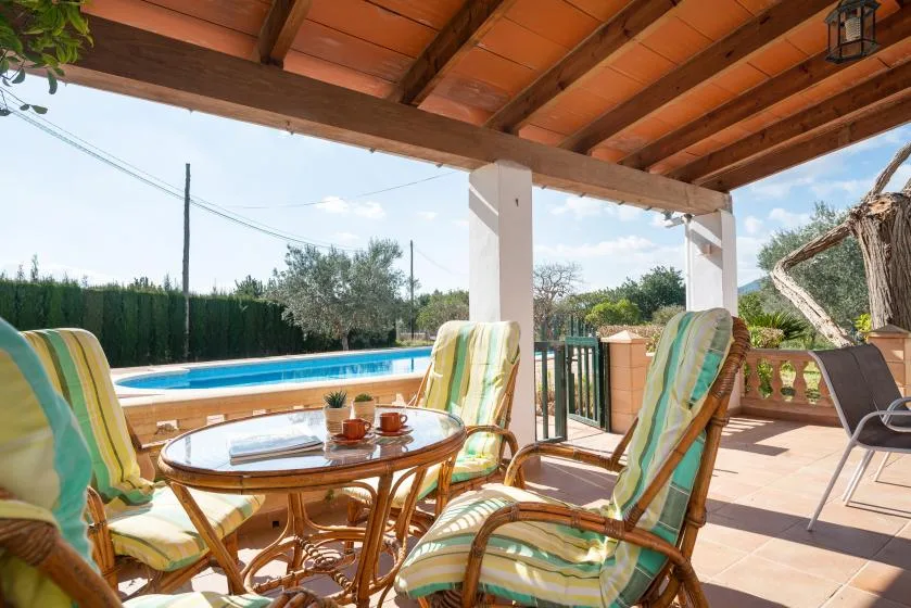 A covered patio with striped seating and a swimming pool visible beyond.