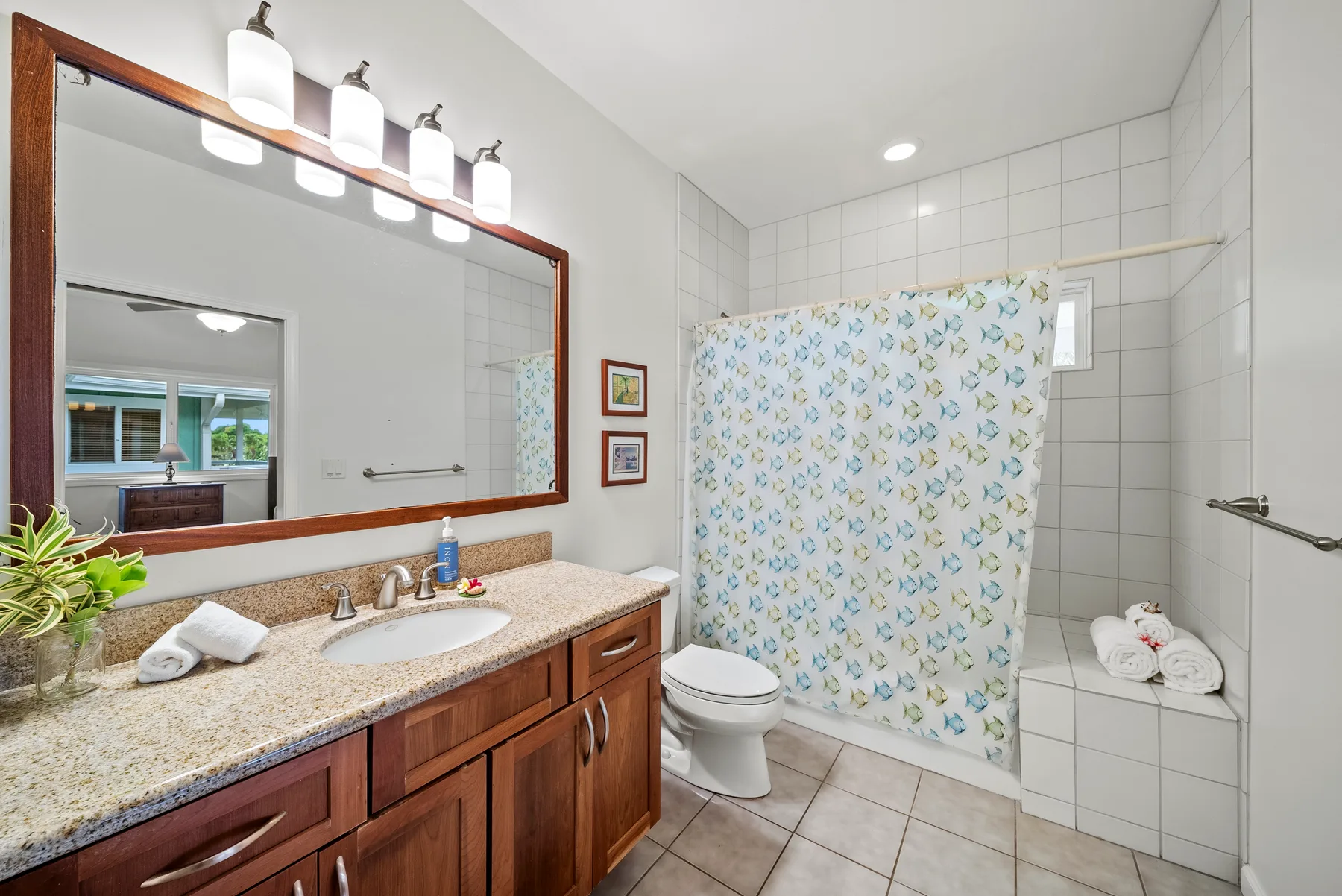 Un baño alicatado con lavabo, inodoro y cortina de ducha floral.