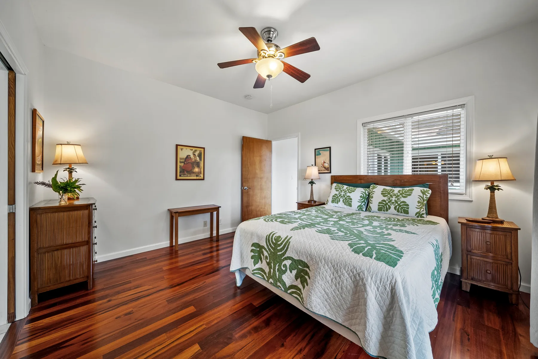 Un dormitorio con cama de madera, ropa de cama con motivos de hojas y suelo de madera pulida.