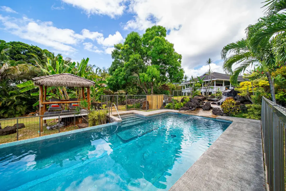 Una piscina al aire libre está rodeada de exuberante vegetación tropical.