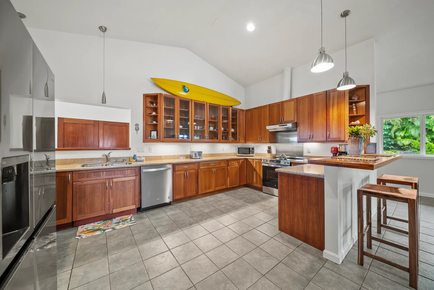 Una cocina amplia con gabinetes de madera, una isla central y un kayak amarillo sobre los armarios.
