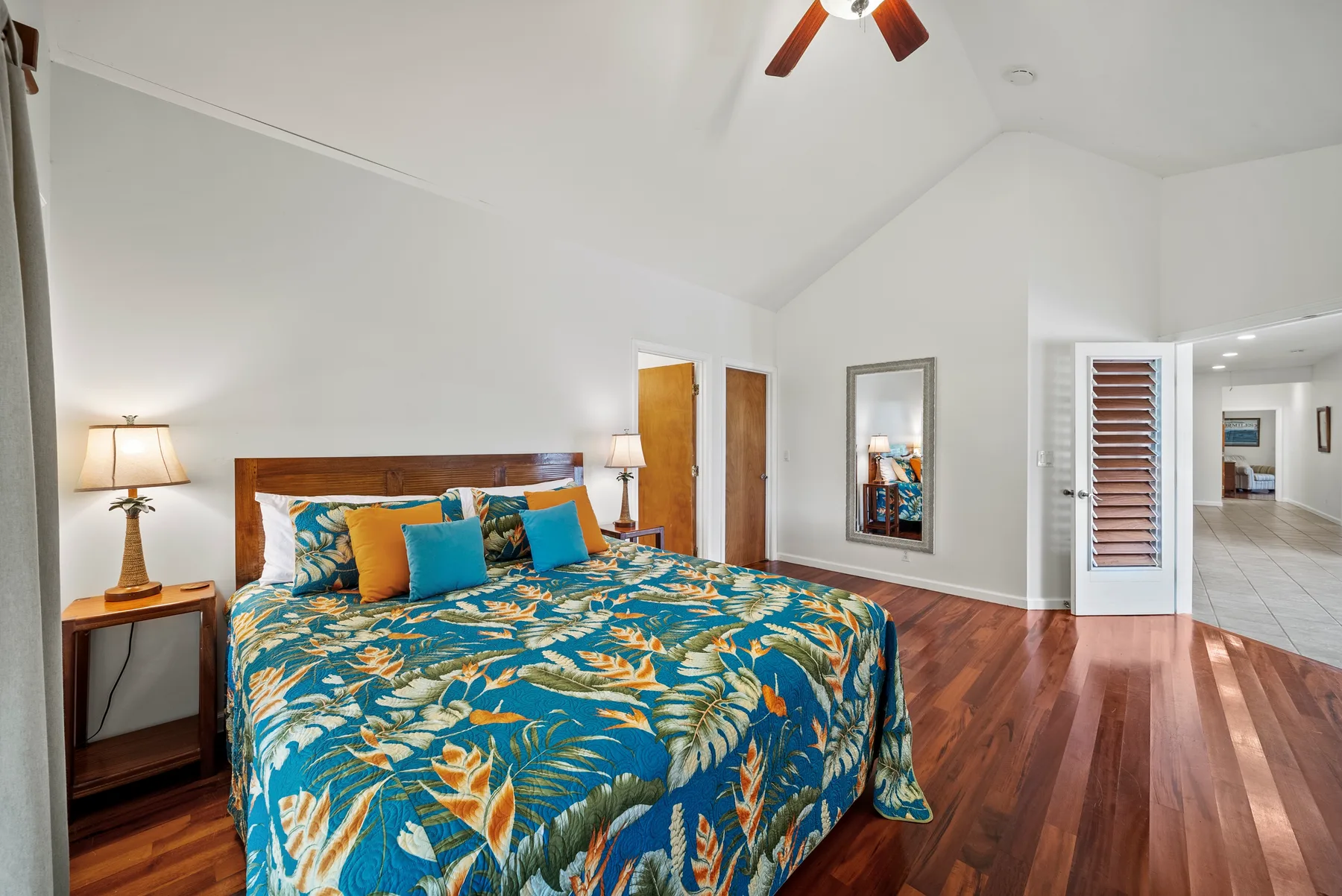 Un dormitorio con una cama cubierta con ropa de cama azul estampada y suelo de madera.