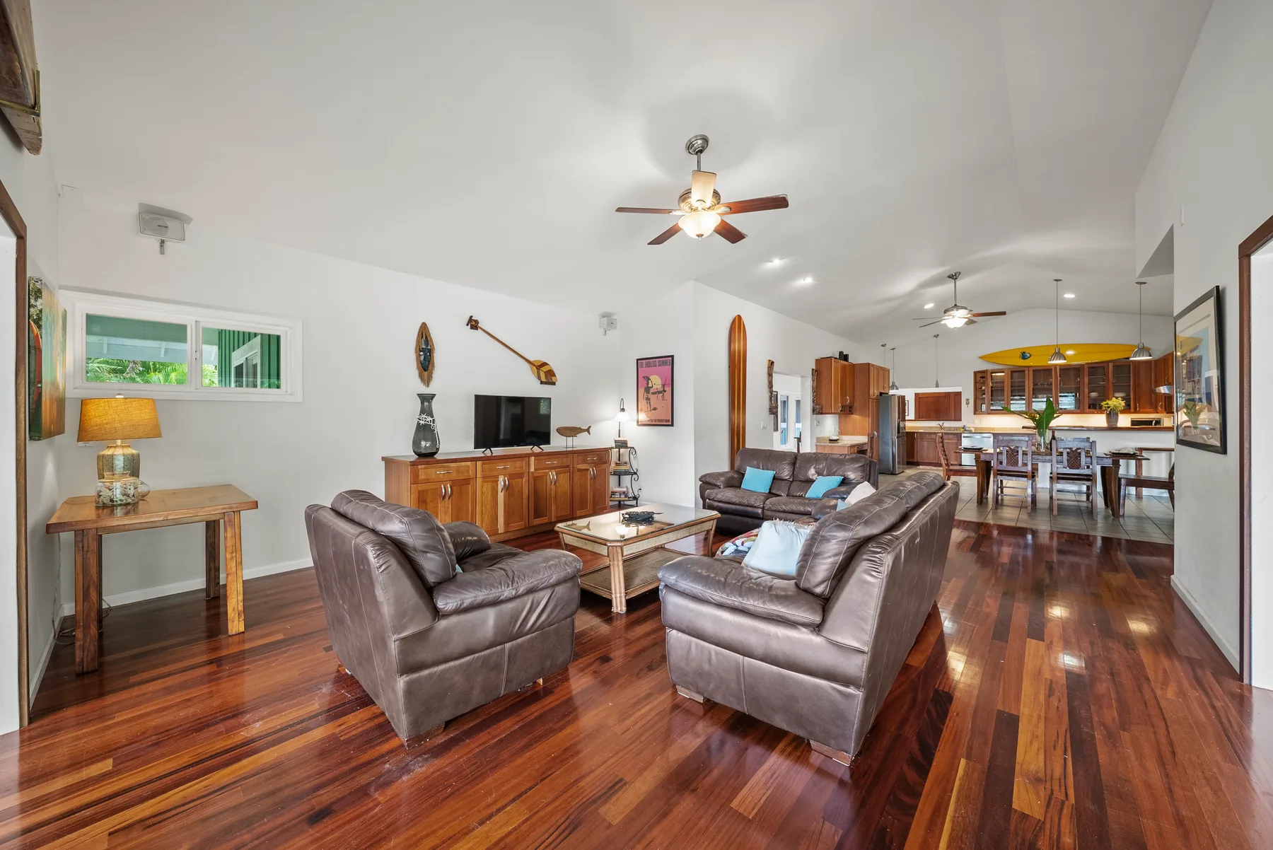 Una sala de estar con asientos y piso de madera se abre a un comedor.
