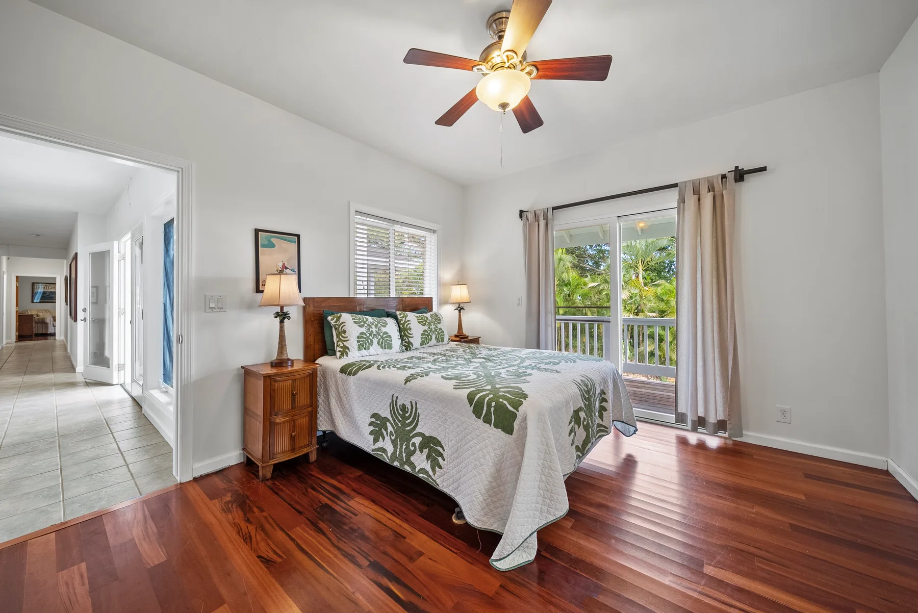 Un dormitorio con una cama junto a una ventana grande con vistas a la vegetación.