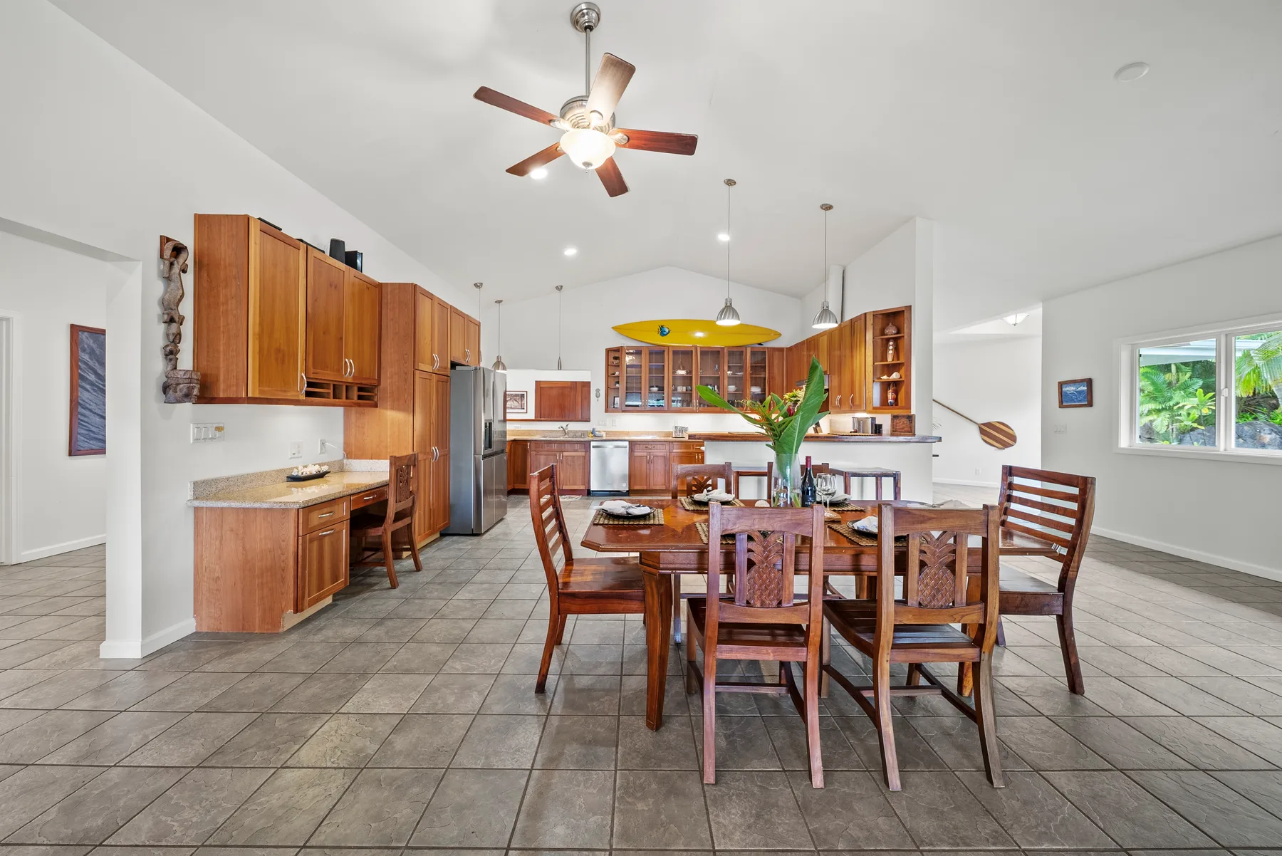 Cocina y comedor abiertos con gabinetes de madera y una mesa grande.