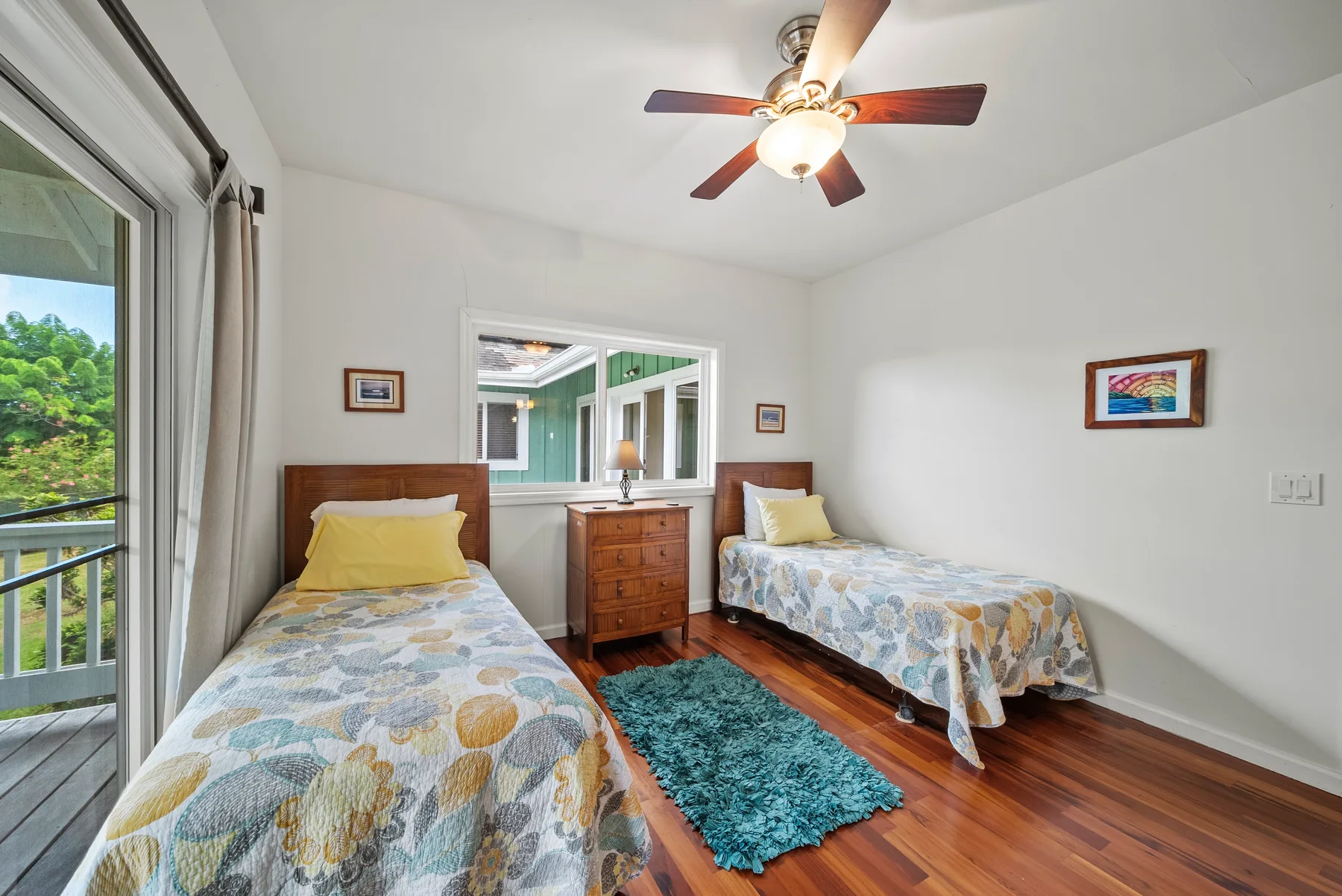 Un dormitorio con dos camas, una cómoda de madera y un ventilador de techo.