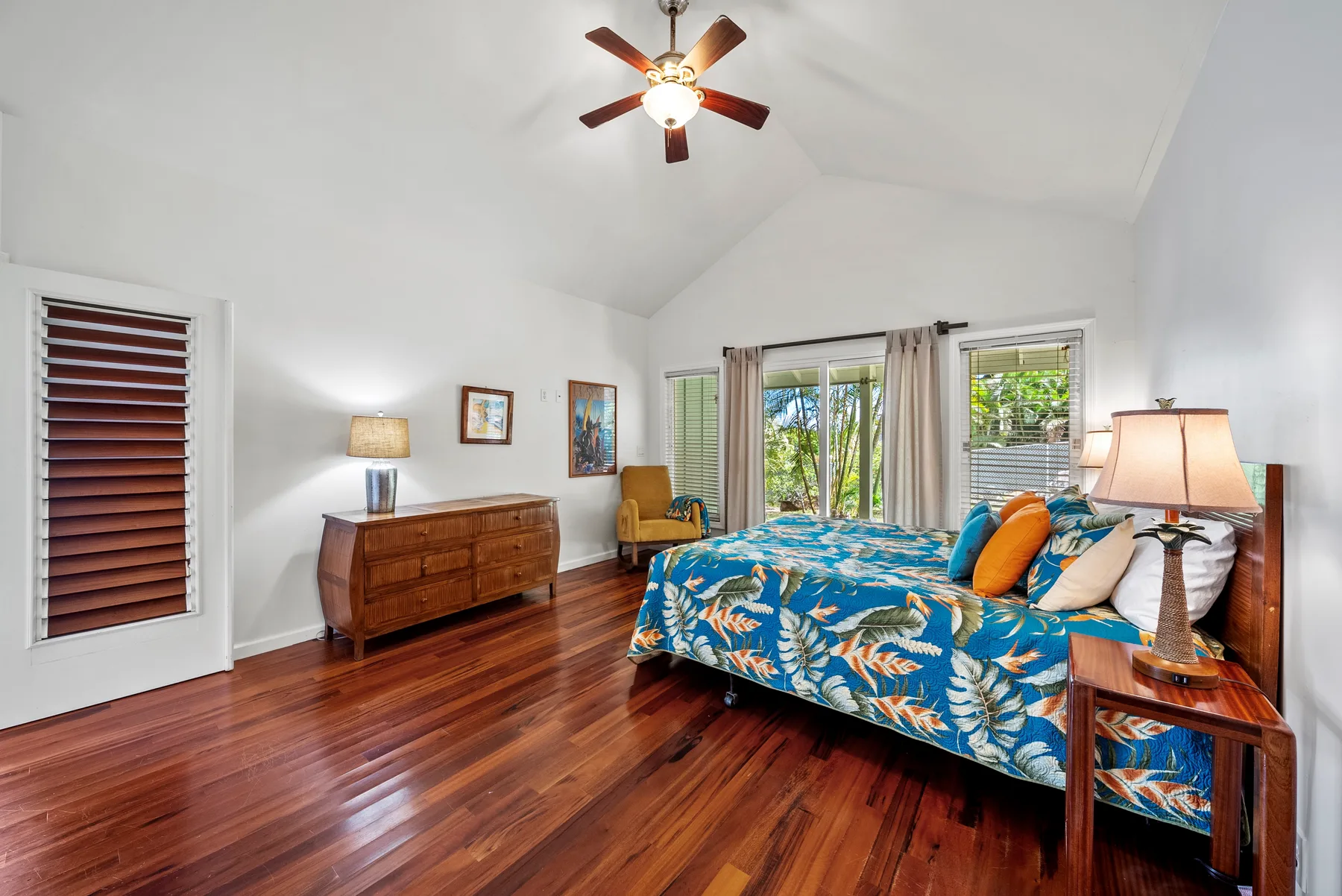 Un dormitorio luminoso tiene una cama con estampado colorido y suelo de madera pulida.