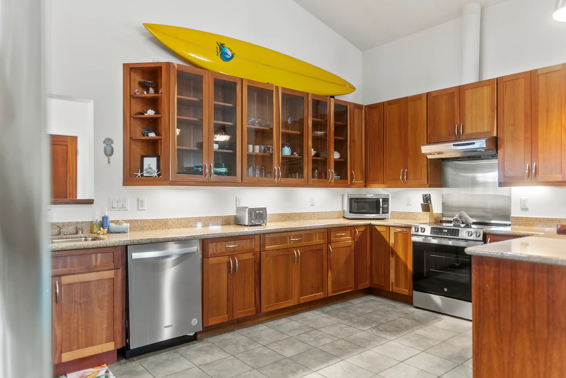 Una cocina con gabinetes de madera, electrodomésticos de acero inoxidable y un kayak amarillo encima.