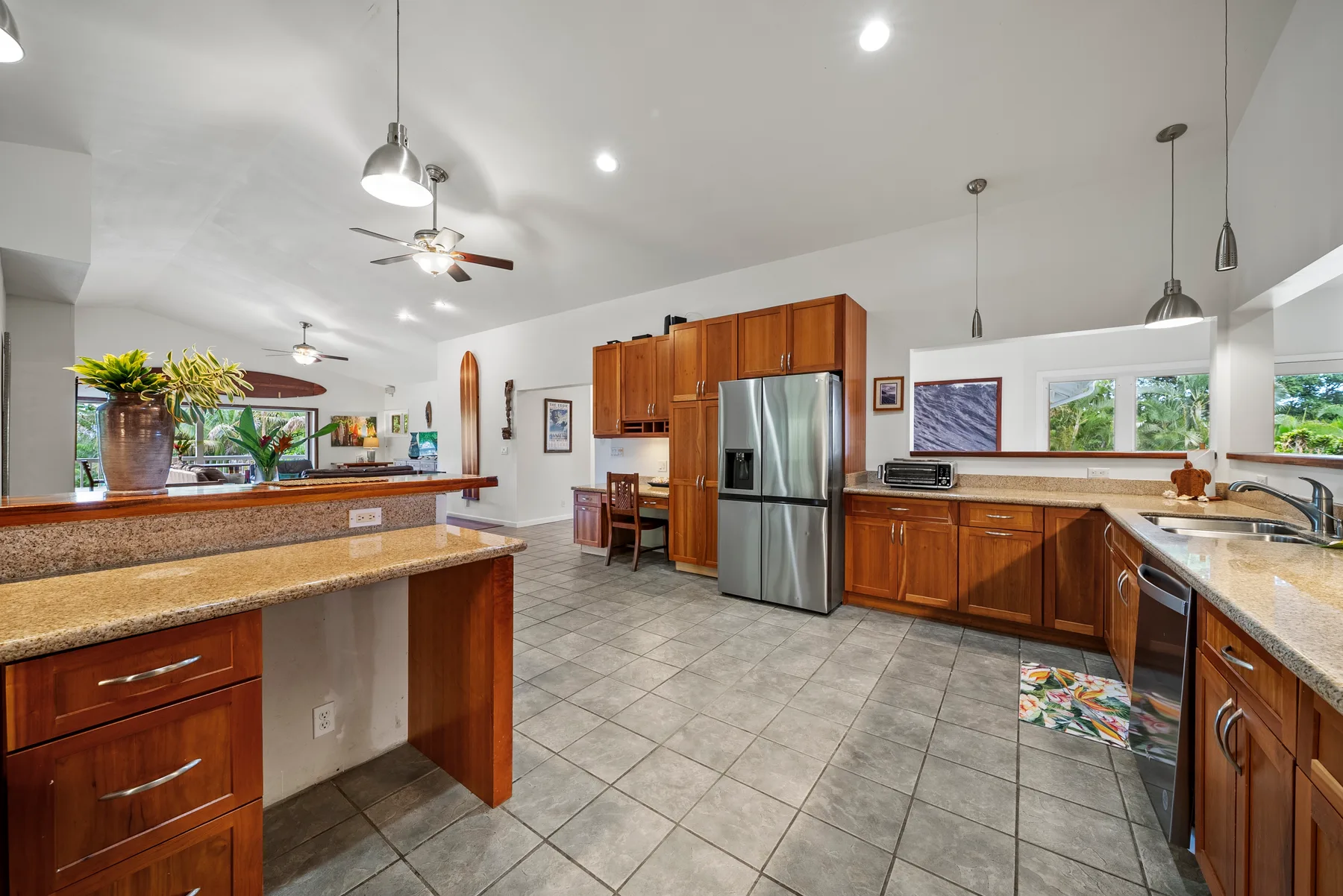 Una cocina amplia con gabinetes de madera, un refrigerador de acero inoxidable y piso de baldosas.