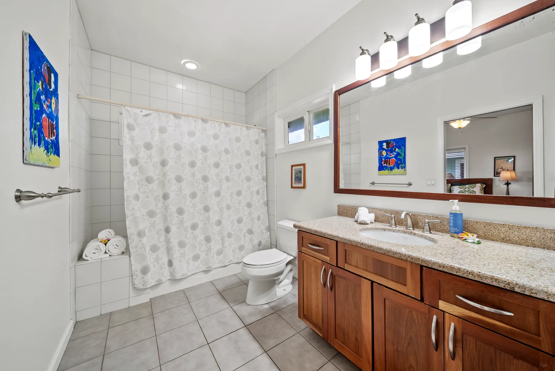 Un baño con zona de ducha alicatada, inodoro y un largo tocador.