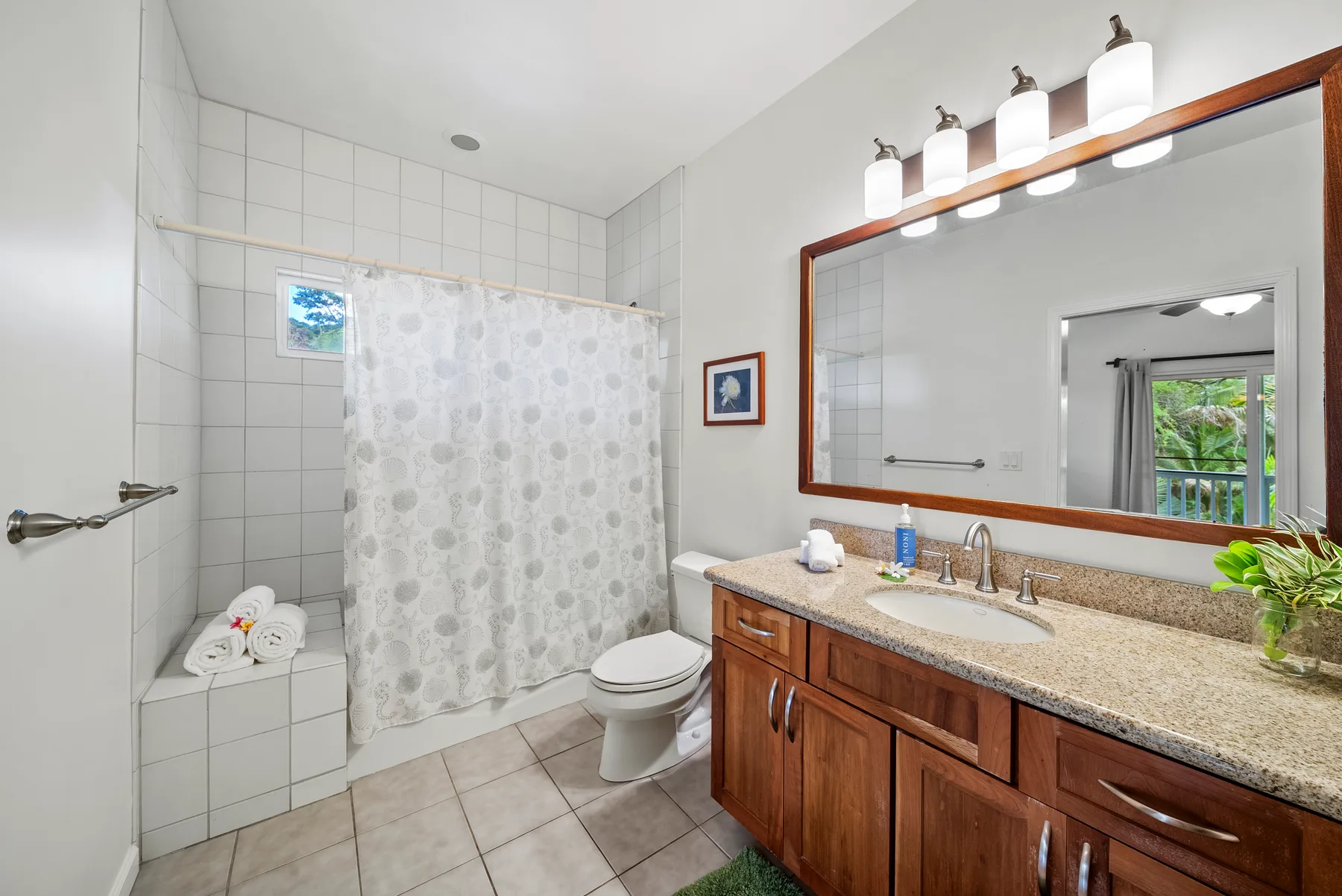 Un baño con zona de ducha alicatada, inodoro y un largo tocador.