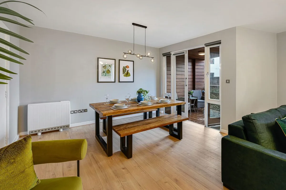Un comedor con una mesa y un banco de madera junto a una puerta abierta.