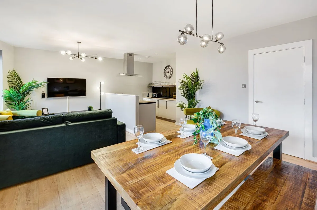 Un espacio abierto de sala y comedor con una mesa de madera preparada para comer.