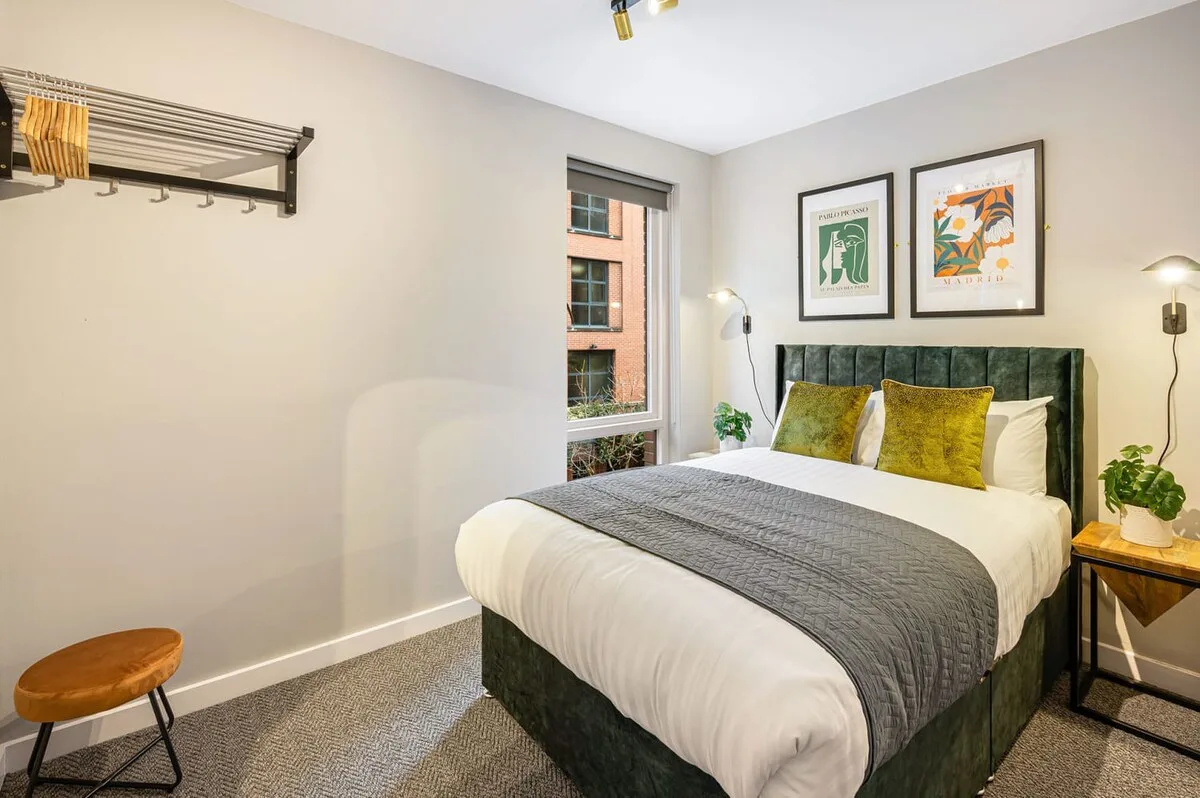 Un dormitorio con una cama vestida con ropa de cama blanca y almohadas verdes y amarillas.