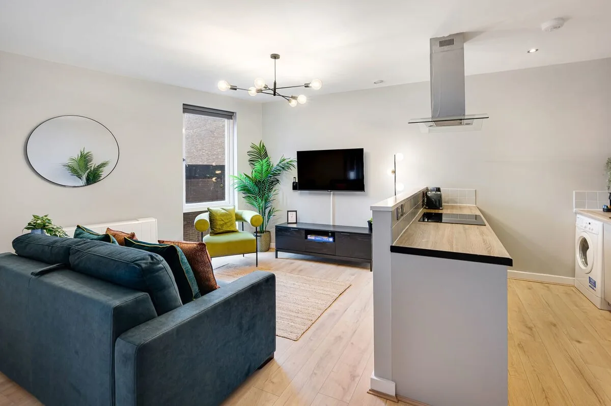 Una luminosa sala de estar y cocina de concepto abierto con televisor y asientos.