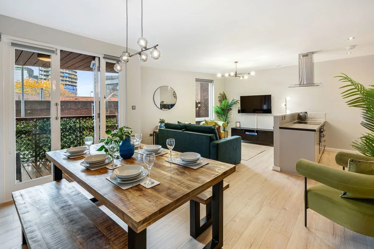 Sala de estar y comedor de concepto abierto, con una mesa puesta junto a grandes ventanas.