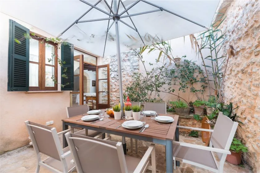Comedor al aire libre con una mesa y asientos bajo una sombrilla grande.